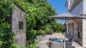 A patio area with wicker furniture, a pool, and lush greenery. - Romantika by Interhome (Rovinj)