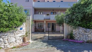 A two-story building with a stone wall entrance, a metal gate, and a paved driveway. - Romantika by Interhome (Rovinj)