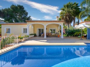 A poolside area with a covered patio, a seating area, and a pool.