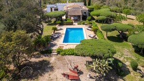 Eine Villa mit Swimmingpool, umgeben von gepflegten Gärten und Bäumen.