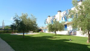 A residential area with a swimming pool, a grassy lawn, and a building with blue balconies. - Vacation home Minini by Interhome (L'Ampolla)