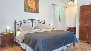 Una camera da letto con un letto, comodini, un'armadietto in legno e un quadro appeso al muro.