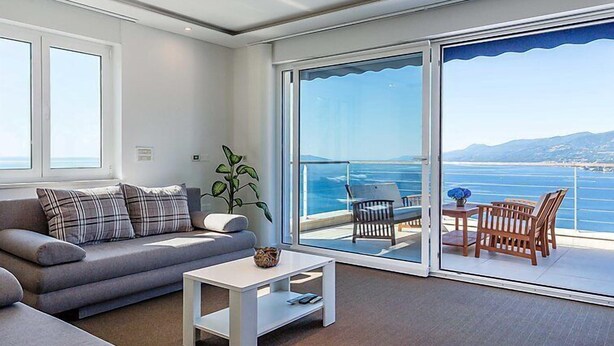 A modern living room with a sofa, a coffee table, and a view of the sea through large sliding glass doors. - Vacation home Vista by Interhome (Opatija/Matulji)