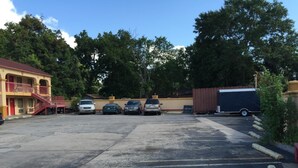 En parkeringsplats med flera bilar, en byggnad med ett rött tak och en stor lastbil.
