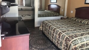 Ett hotellrum med en säng, ett skrivbord, en spegel och ett badrum som syns genom en valvöppning.