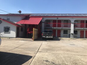 A building with a red roof and solar panels, a gated entrance, and a parked truck. - Regency Inn and Suites (Houston)