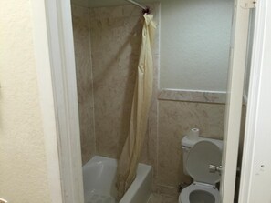 A bathroom with a bathtub, toilet, and shower curtain. - Regency Inn and Suites (Houston)
