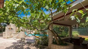 Un patio con pared de piedra, un árbol y una zona de estar cubierta.