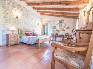 Une chambre confortable avec un mur en pierre, un lit en bois et une chaise rustique.