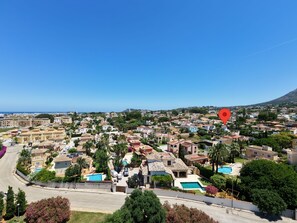 Zona residencial costera con casas, cielo azul despejado y una montaña al fondo.