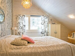A bedroom with a bed, a window with curtains, a clock, and a wardrobe.