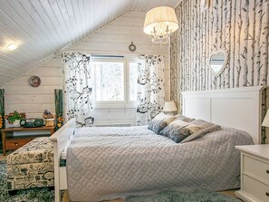 Une chambre à coucher avec un grand lit, une commode, une coiffeuse, un miroir et une fenêtre avec des rideaux.