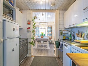 A kitchen with a refrigerator, stove, and various kitchen utensils. There is a dining area with a table and chairs.