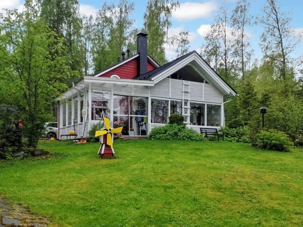 A house with a red roof, white walls, and a glass front.