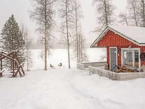 A snow-covered landscape with a red cabin and a wooden deck.