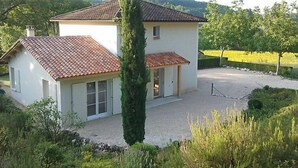 Una casa de dos pisos con techo de tejas, un garaje pequeño adosado y entrada de grava.