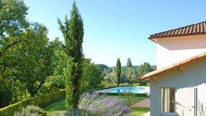 Una casa con piscina, rodeada de abundante vegetación y un jardín cuidado.