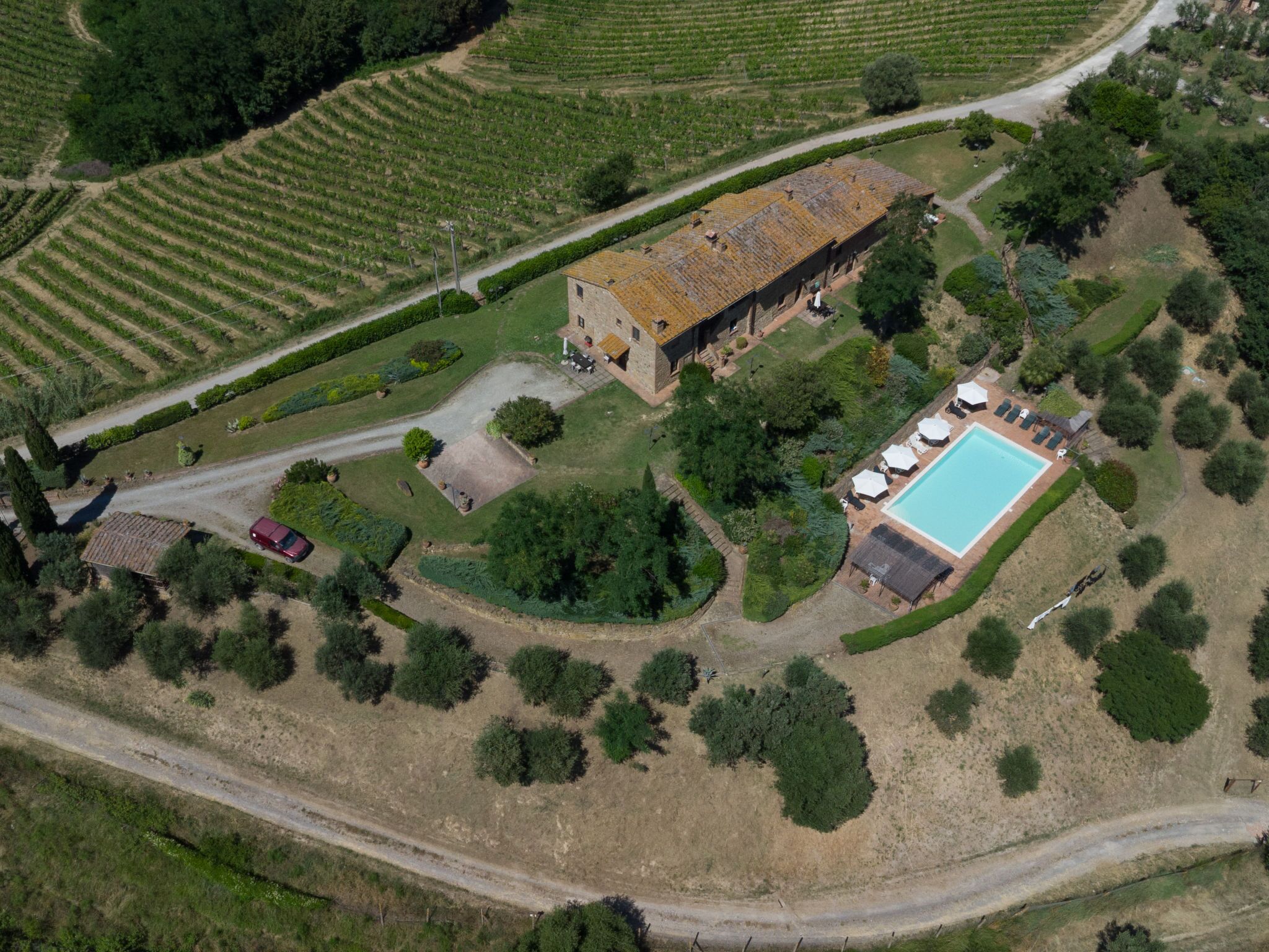 Vista aerea di una proprietà con un edificio grande, una piscina e giardini circostanti.