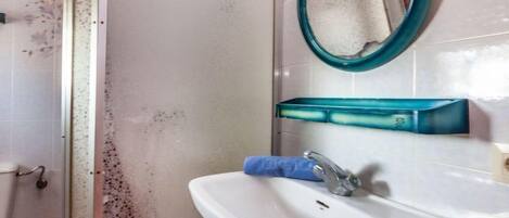 A bathroom with a white sink, a blue towel, and a green-framed mirror.