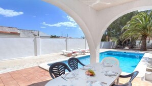 A dining area with a pool, outdoor chairs, and a table set for two. - Villa Zozo by Interhome (L'Ametlla de Mar)