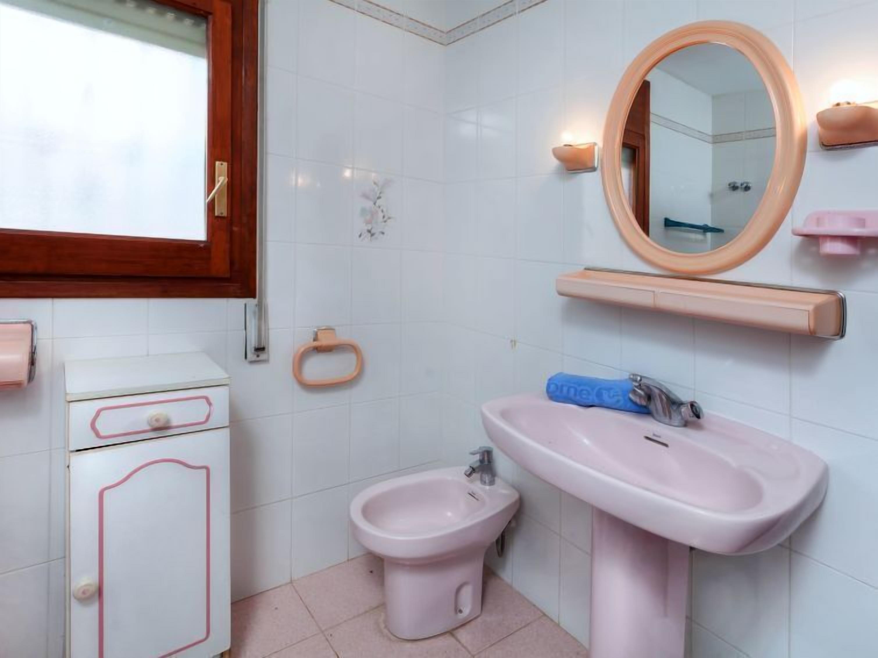 Un baño con inodoro, lavabo, espejo, toallero y bidé.