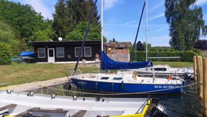 A marina with boats docked, a small building, and greenery in the background. - Güstrower Chaussee by Interhome (Krakow am See)