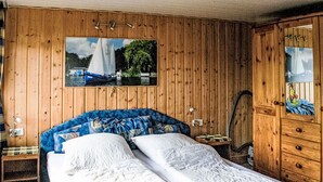 A wooden-paneled room with a bed, a nightstand, a lamp, and a painting of a sailboat on the wall. - Güstrower Chaussee by Interhome (Krakow am See)