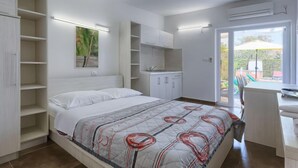 Camera da letto con un letto, scaffalature integrate, una scrivania e vista su un patio esterno.