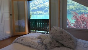 Ein Schlafzimmer mit Bett, Seeblick und einem Balkon mit Geländer.