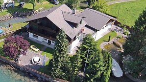 Ein großes Haus mit geneigtem Dach, einem Schwimmbad und einem Steg, der ins Wasser führt.