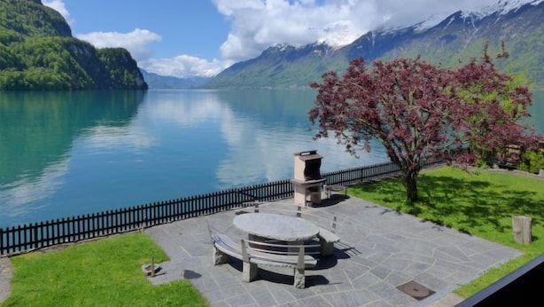 Eine Terrassenausstattung am See mit Steintisch und -stühlen, einem Grill und Blick auf einen Bergsee.