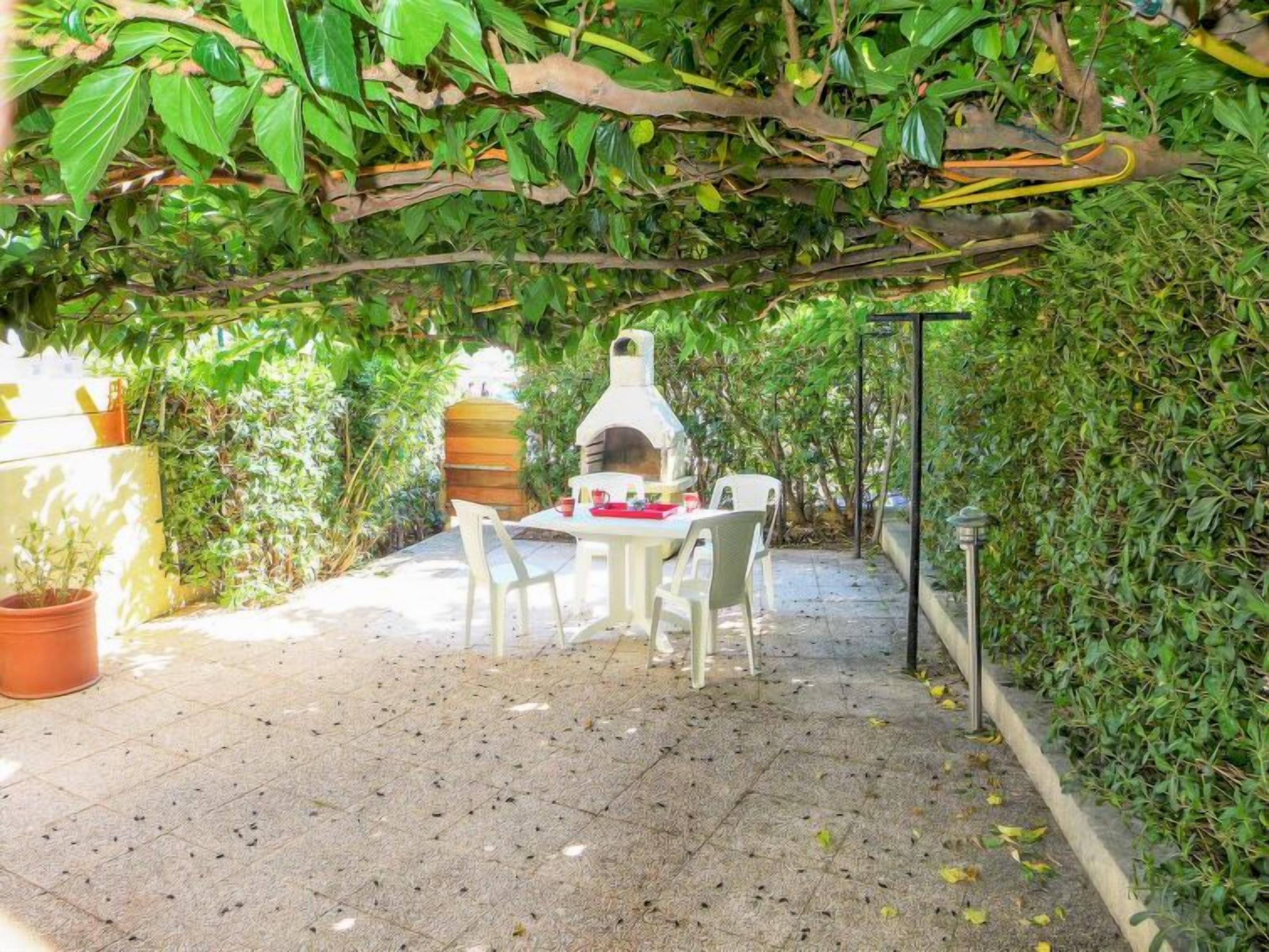 An outdoor patio with a brick floor, a white table, and chairs.