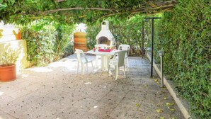 An outdoor patio with a brick floor, a white table, and chairs.