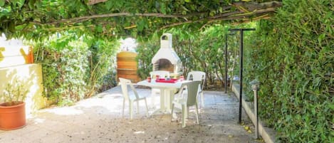 Un patio al aire libre con suelo de ladrillo, una mesa blanca y sillas.