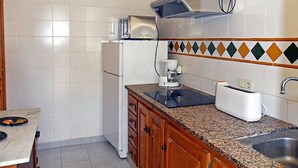 A compact kitchen with white tiles, a built-in oven, a coffee maker, and a toaster. - Josiane by Interhome (L'Escala)
