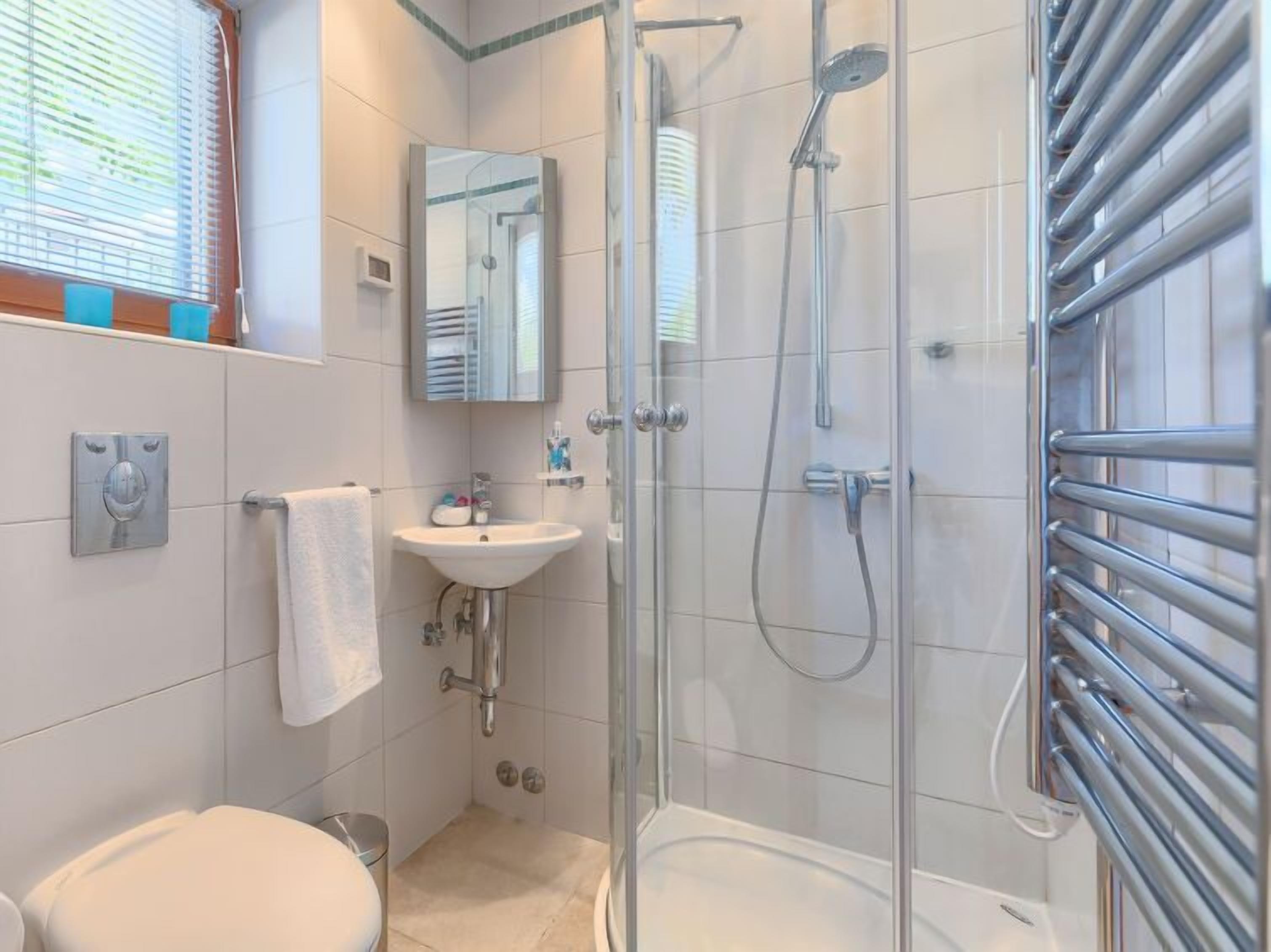 Une salle de bain moderne avec une douche à parois de verre, un lavabo blanc et des toilettes.