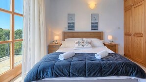 A bedroom with a large bed, two bedside tables with lamps, a wooden wardrobe, and a balcony view. - Vacation home Nini by Interhome (Buje)