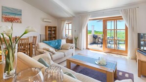 A spacious living room with a sofa, coffee table, and a dining area with chairs. There is a bookshelf and a TV on a stand. - Vacation home Nini by Interhome (Buje)
