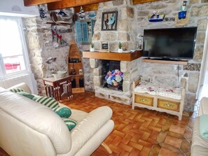 Un salon chaleureux avec une cheminée en pierre, un téléviseur et un canapé confortable.