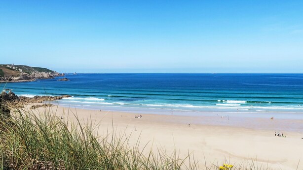 Een strand met heldere lucht, rustig water en een zandstrand.