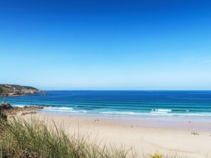 Une plage avec un ciel dégagé, une eau calme et un rivage sablonneux.