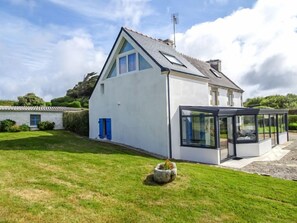 Une maison moderne avec un toit en pente, une véranda et une pelouse bien entretenue.