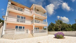 Un edificio de varios pisos con balcones, un patio empedrado de piedra y un parterre de flores.