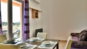 Un comedor con una mesa dispuesta para dos personas, un sofá y una ventana con cortinas.