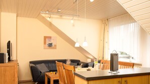 A compact living space with a kitchenette, a dining area, and a sofa. - Strandläufer by Interhome (Norddeich)