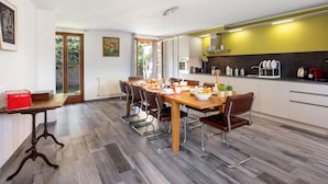 Una cocina moderna con comedor, que incluye una mesa de madera, sillas y vistas al exterior.