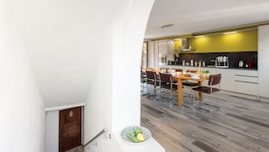 Una cocina moderna con comedor, que cuenta con una escalera que baja a un nivel inferior.