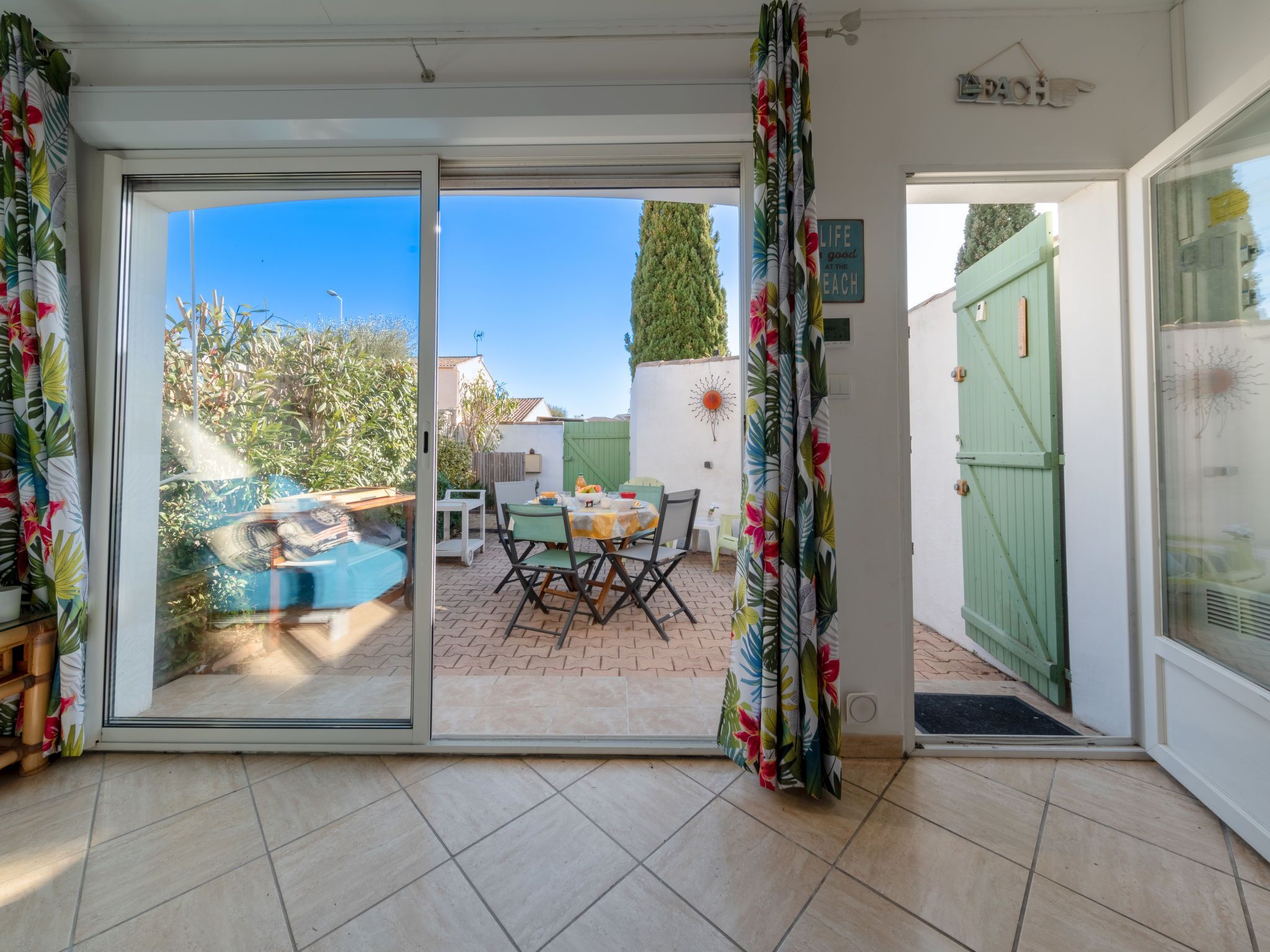 A patio area with a table and chairs, a small pool, and a green gate.