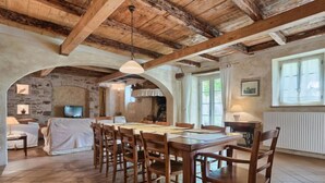 Un'accogliente sala da pranzo in stile rustico con un tavolo e sedie in legno, pareti in pietra e un soffitto a volta.