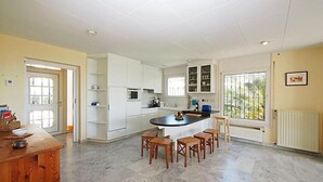 A spacious kitchen with white cabinetry, a central island, and a dining area with wooden chairs. - Vacation home Bilbao by Interhome (Roses)